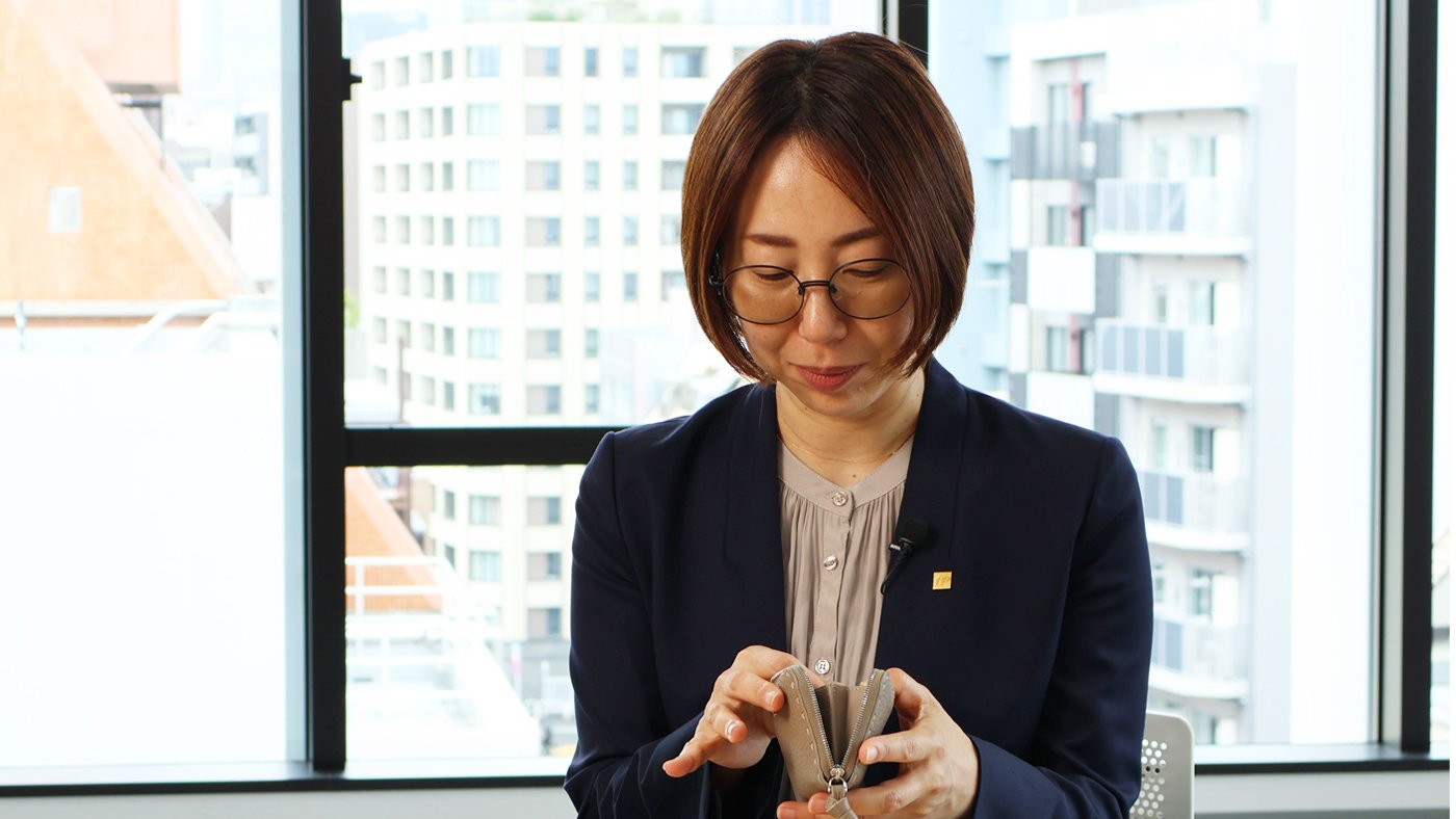 財布からお守りをとり出す島野友加里FPの画像